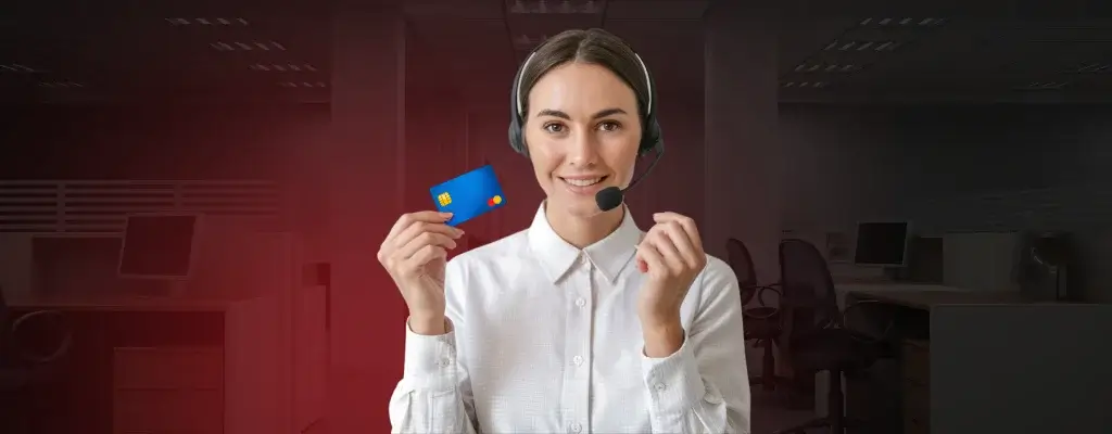 A woman wearing a white top and headset confidently holding a credit card